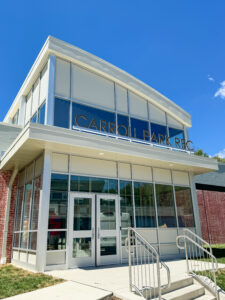 View of the Carroll Park Rec Center entrance which has a large atrium full of windows.