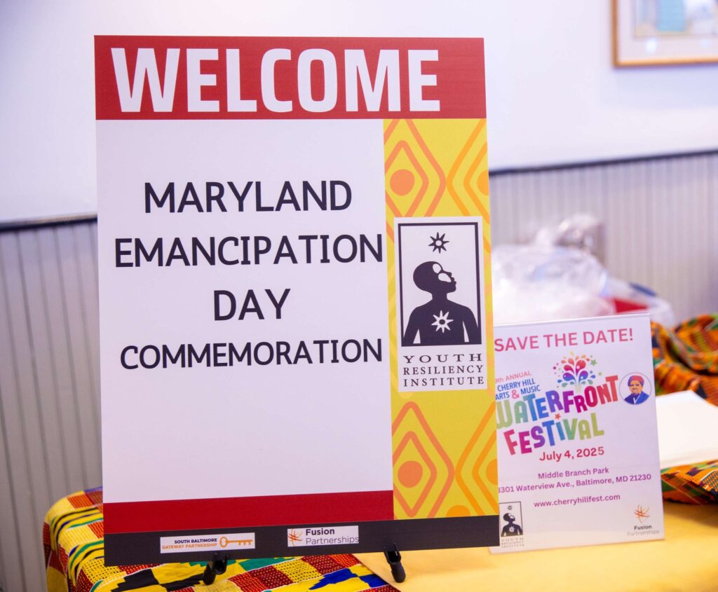 A welcome sign for the event with the YRI logo is on a table with a yellow table cloth.